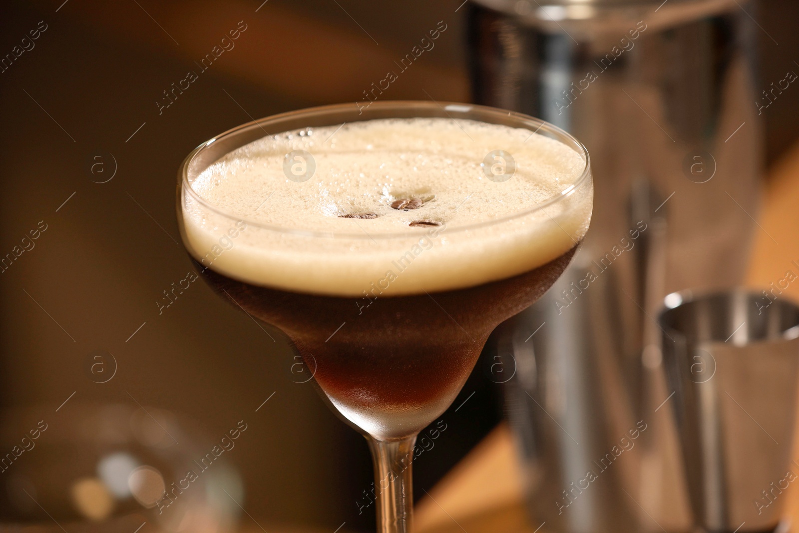 Photo of Delicious espresso martini in glass on blurred background, closeup