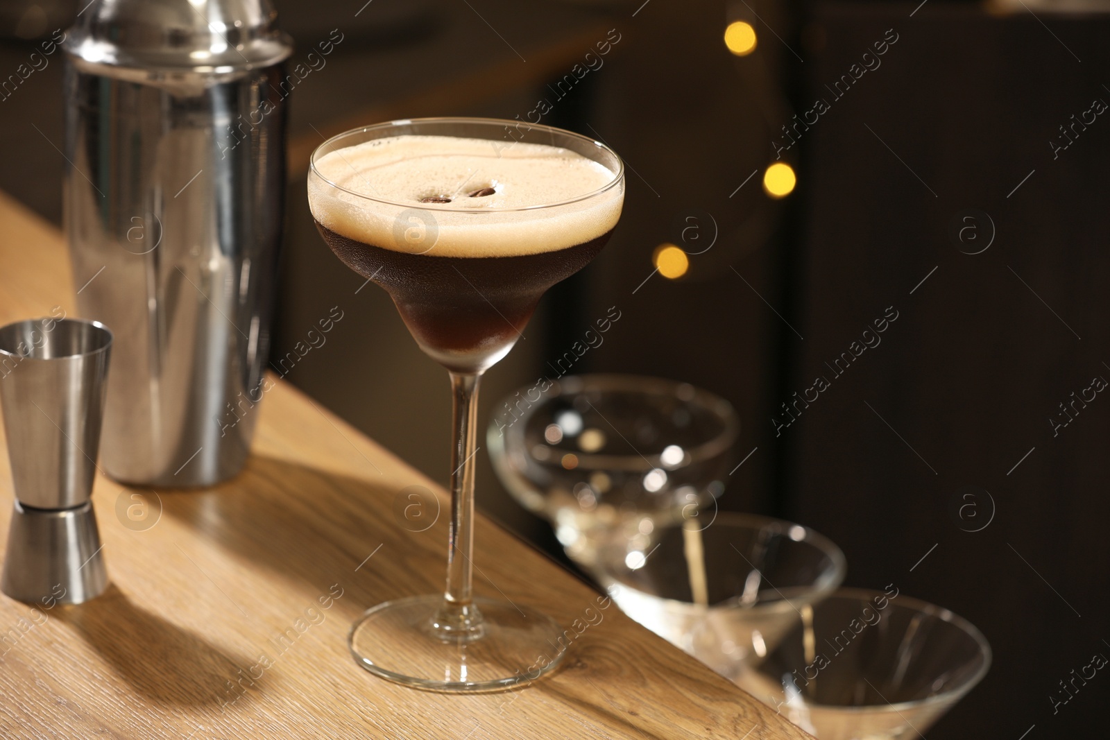 Photo of Glass with delicious espresso martini on wooden table in bar