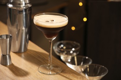 Photo of Glass with delicious espresso martini on wooden table in bar