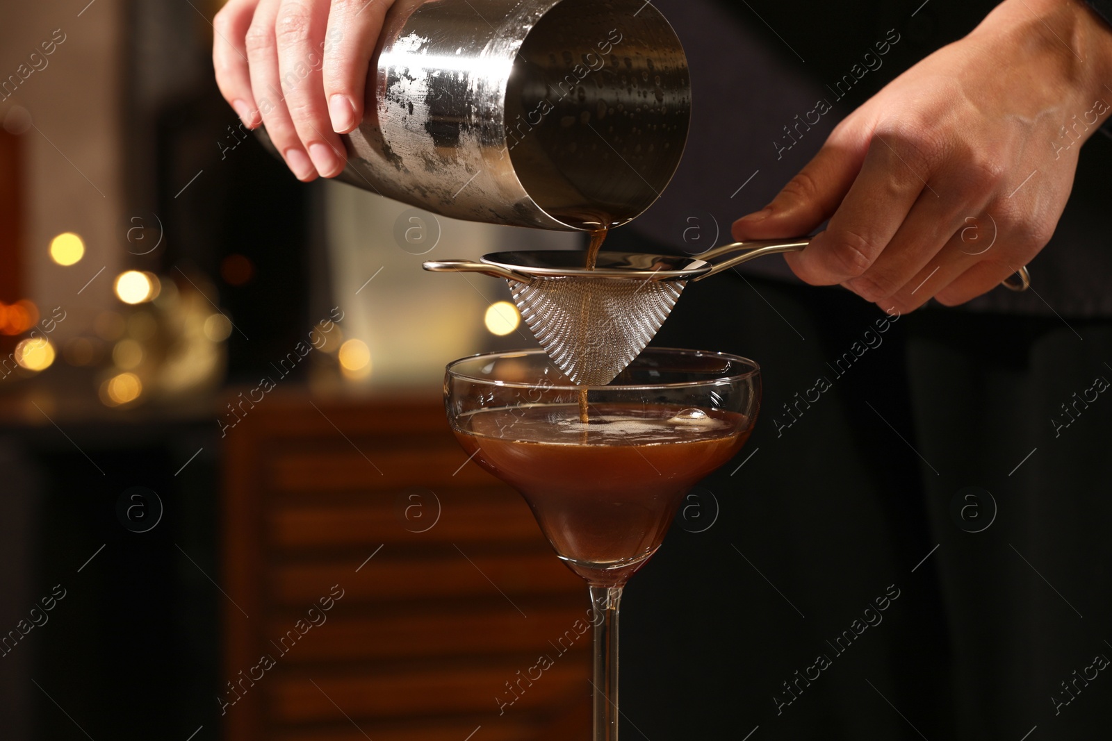 Photo of Bartender making delicious espresso martini in bar, closeup