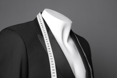 Photo of Male mannequin with black jacket and measuring tape on grey background, closeup