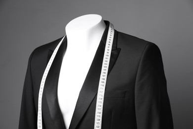 Photo of Male mannequin with black jacket and measuring tape on grey background, closeup