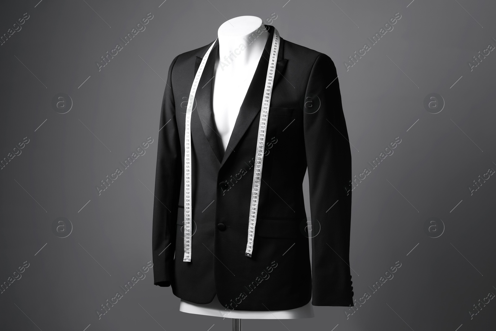 Photo of Male mannequin with black jacket and measuring tape on grey background