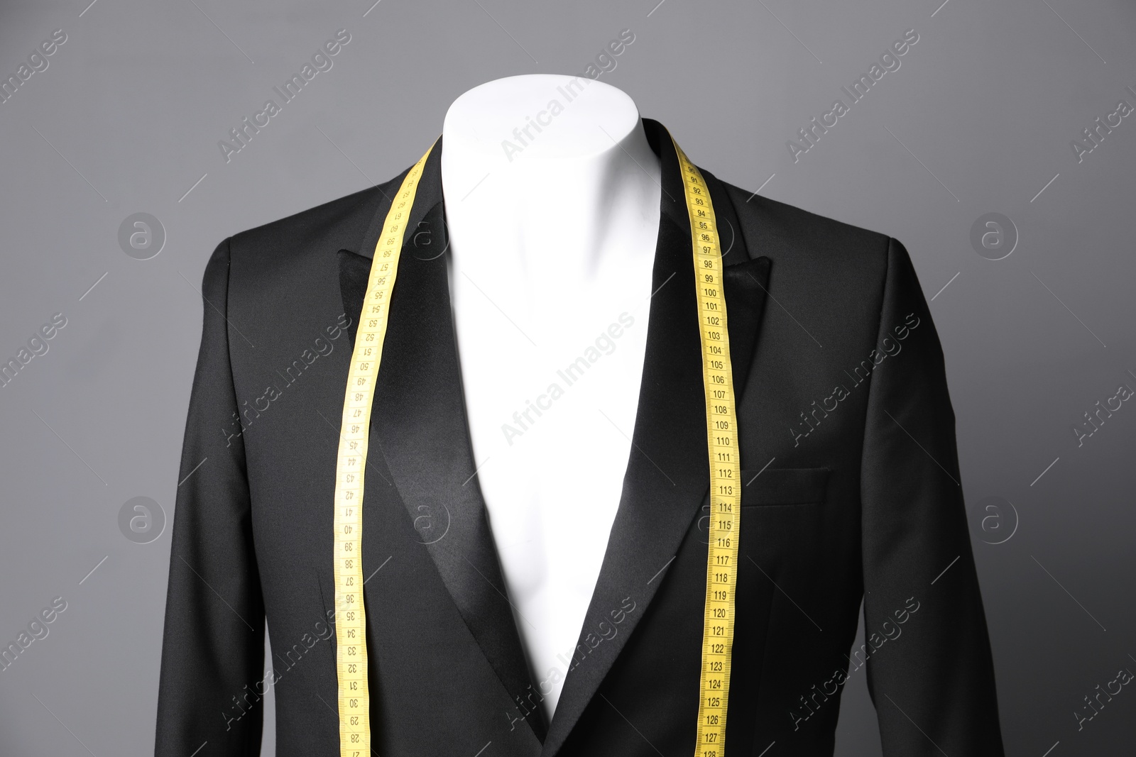 Photo of Male mannequin with black jacket and measuring tape on grey background