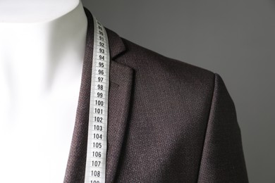 Photo of Male mannequin with brown jacket and measuring tape on grey background, closeup