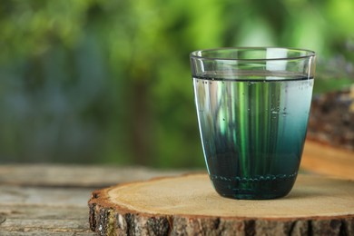 Photo of Soda water in glass on wooden table outdoors, space for text