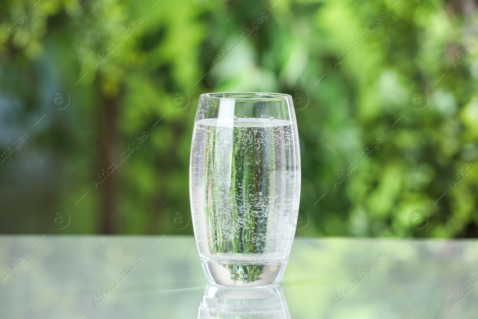 Photo of Soda water in glass on light table outdoors