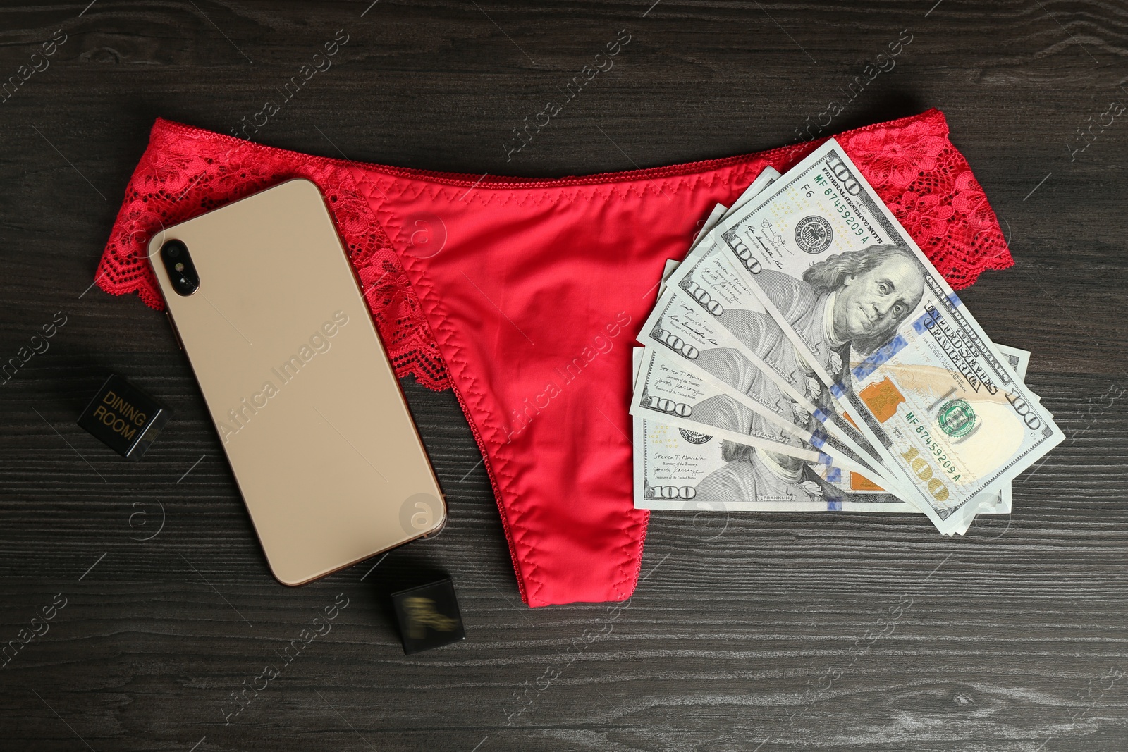 Photo of Sex work. Smartphone, underwear, dice and money on wooden surface, flat lay