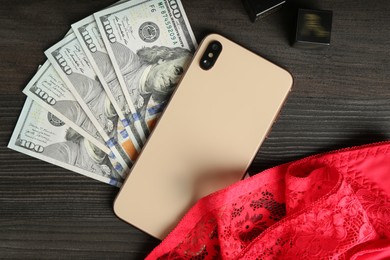 Photo of Sex work. Smartphone, underwear, dice and money on wooden surface, flat lay