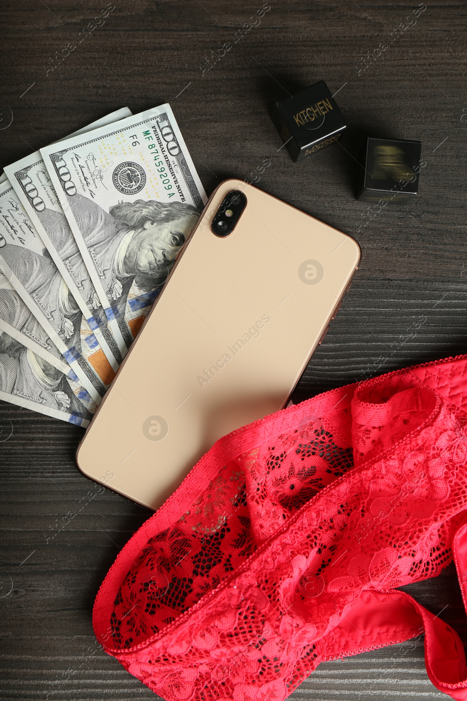 Photo of Sex work. Smartphone, underwear, dice and money on wooden surface, flat lay