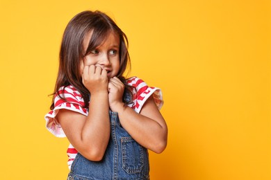 Photo of Scared little girl on orange background. Space for text