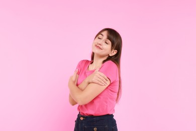 Photo of Young woman hugging himself on pink background