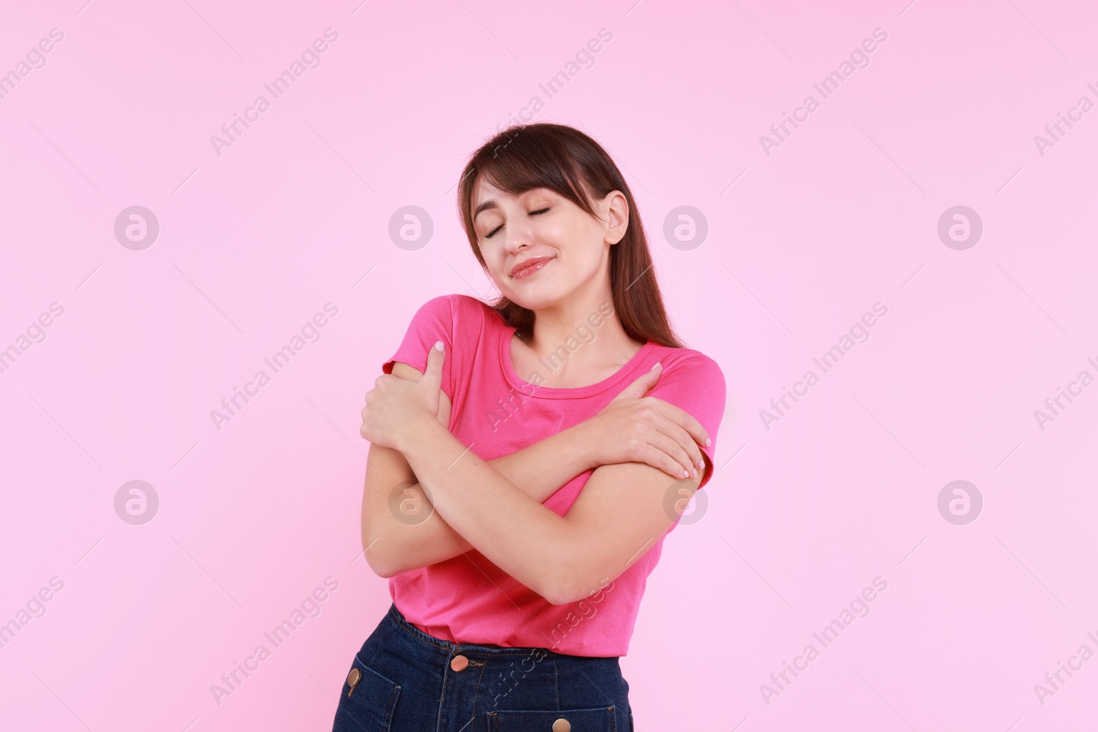 Photo of Young woman hugging himself on pink background