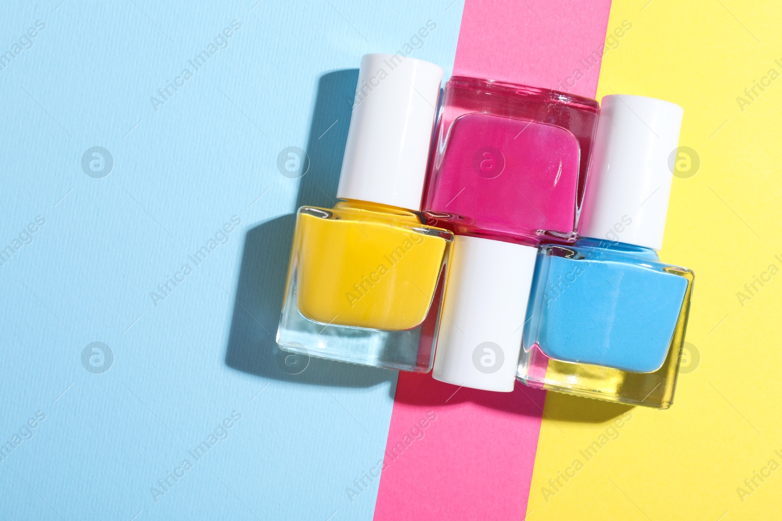 Photo of Bright nail polishes in bottles on color background, flat lay. Space for text