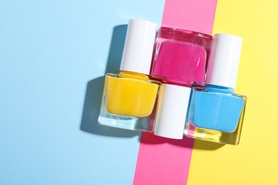 Photo of Bright nail polishes in bottles on color background, flat lay. Space for text