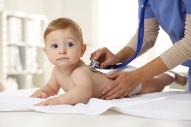 Photo of Pediatrician examining little child with stethoscope in clinic, closeup. Checking baby's health