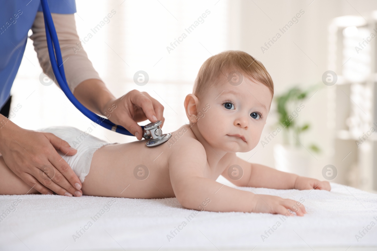 Photo of Pediatrician examining little child with stethoscope in clinic, closeup. Checking baby's health