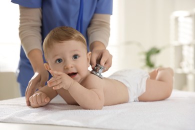 Photo of Pediatrician examining little child with stethoscope in clinic, closeup. Checking baby's health