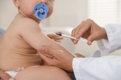 Photo of Pediatrician vaccinating little baby in clinic, closeup