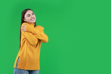 Photo of Charming young woman hugging herself on green background. Space for text