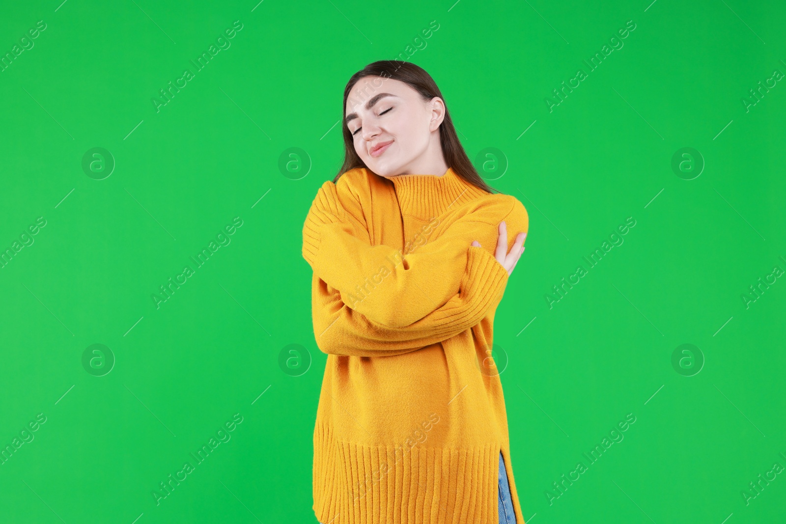 Photo of Charming young woman hugging herself on green background