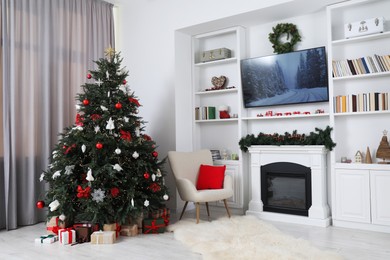 Photo of Beautifully decorated Christmas tree near fireplace in room. Festive interior design