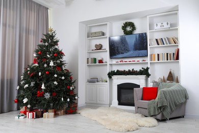 Beautifully decorated Christmas tree near fireplace in room. Festive interior design