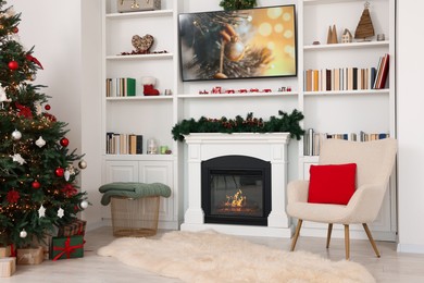 Photo of Beautifully decorated Christmas tree near fireplace in room. Festive interior design