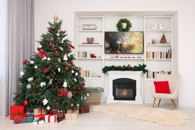 Photo of Beautifully decorated Christmas tree near fireplace in room. Festive interior design