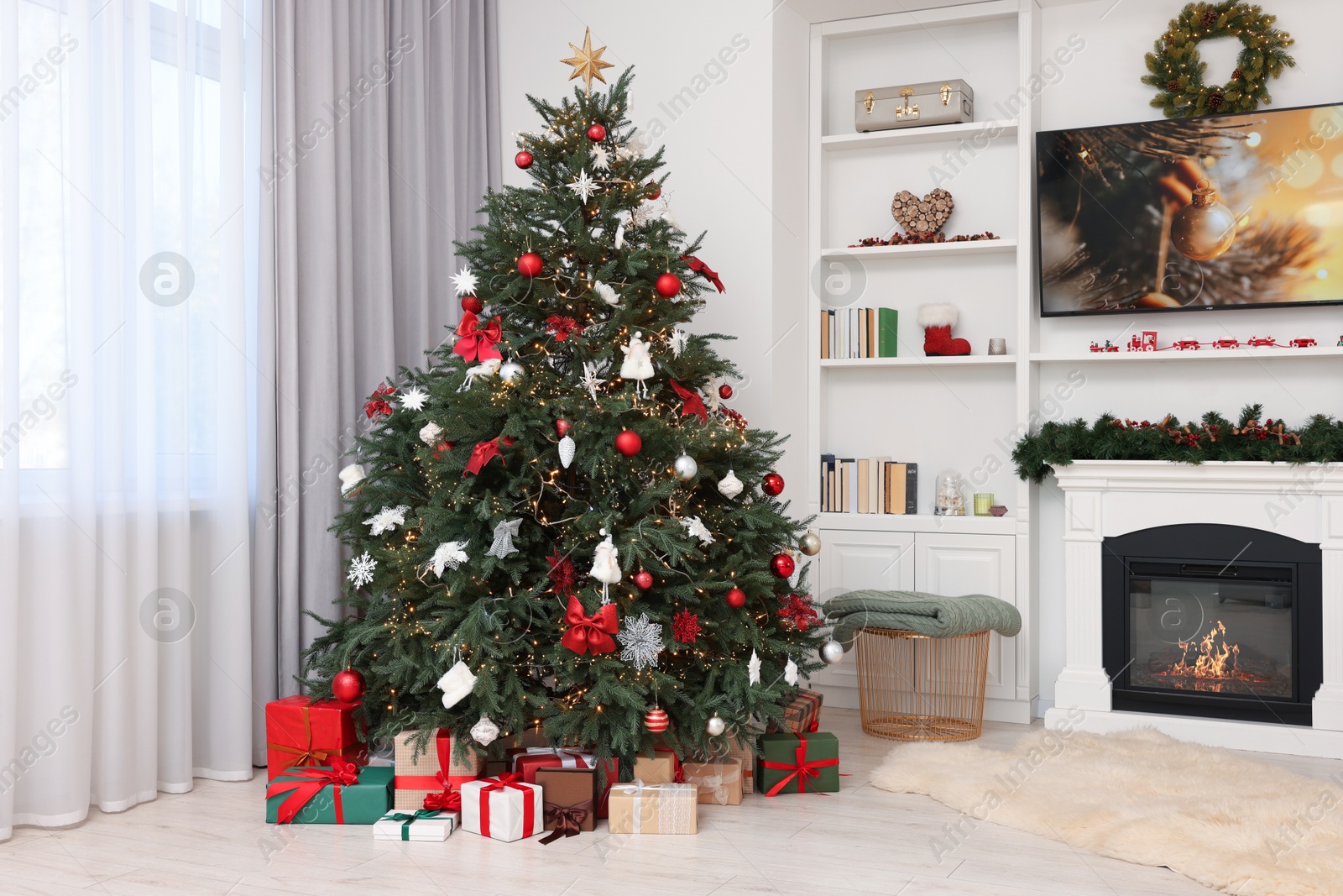 Photo of Beautifully decorated Christmas tree near fireplace in room. Festive interior design