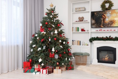 Beautifully decorated Christmas tree near fireplace in room. Festive interior design