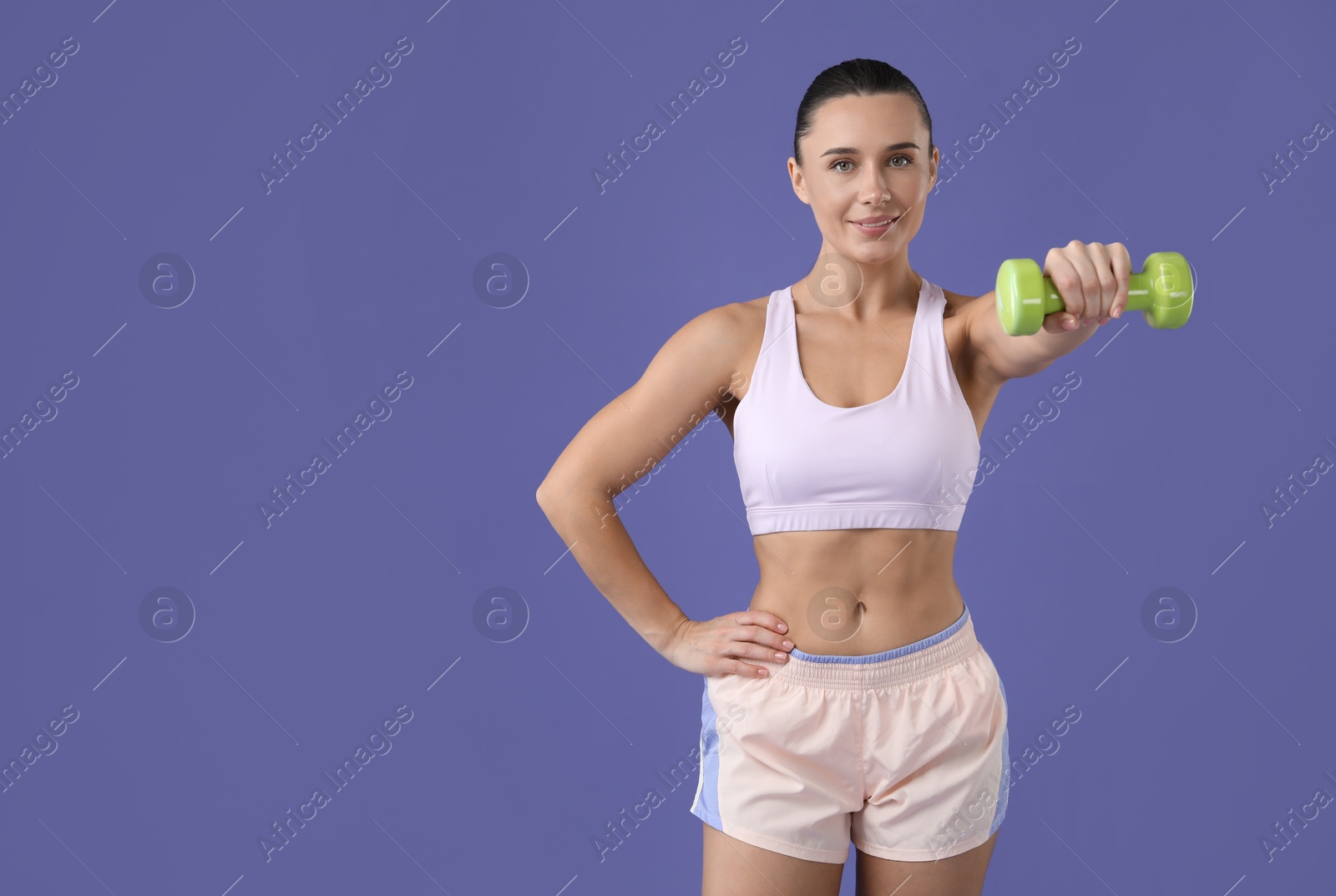 Photo of Woman exercising with dumbbell on purple background, space for text