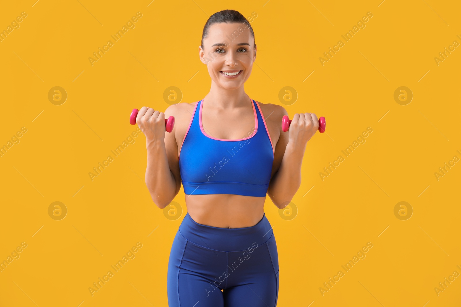 Photo of Woman exercising with dumbbells on orange background