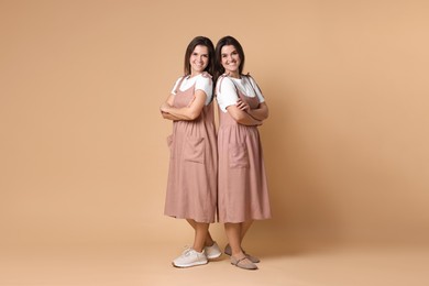 Photo of Portrait of happy twin sisters on pale brown background