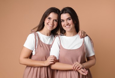 Photo of Portrait of happy twin sisters on pale brown background