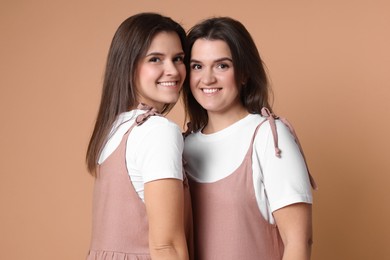 Photo of Portrait of happy twin sisters on pale brown background