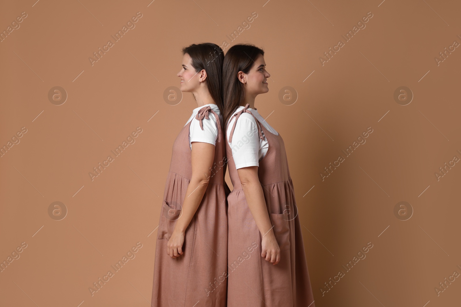 Photo of Portrait of happy twin sisters on pale brown background