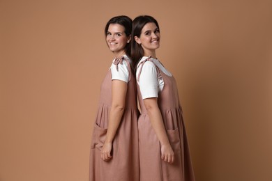 Photo of Portrait of happy twin sisters on pale brown background