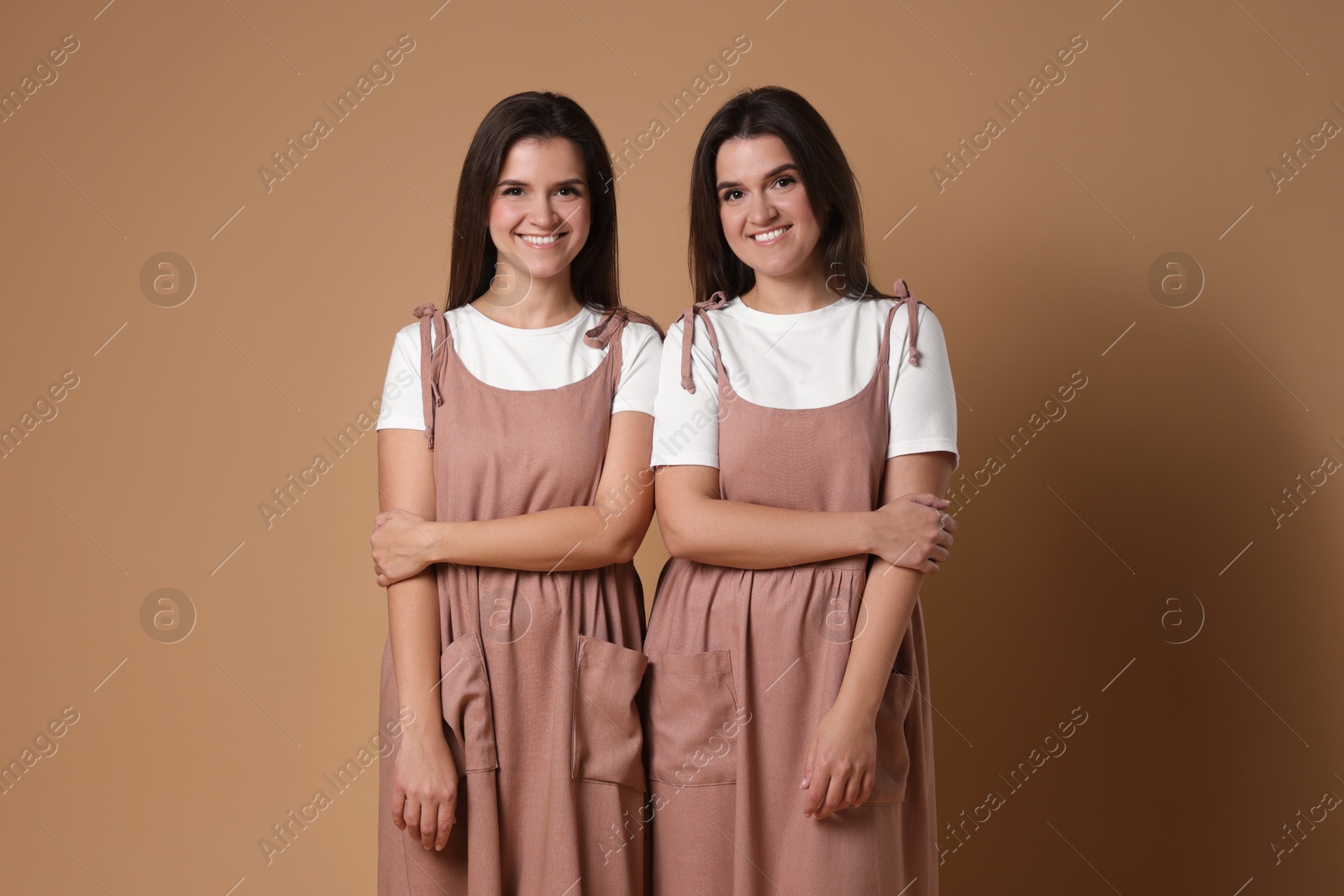 Photo of Portrait of happy twin sisters on pale brown background