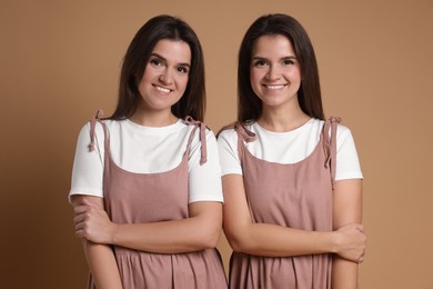 Photo of Portrait of happy twin sisters on pale brown background