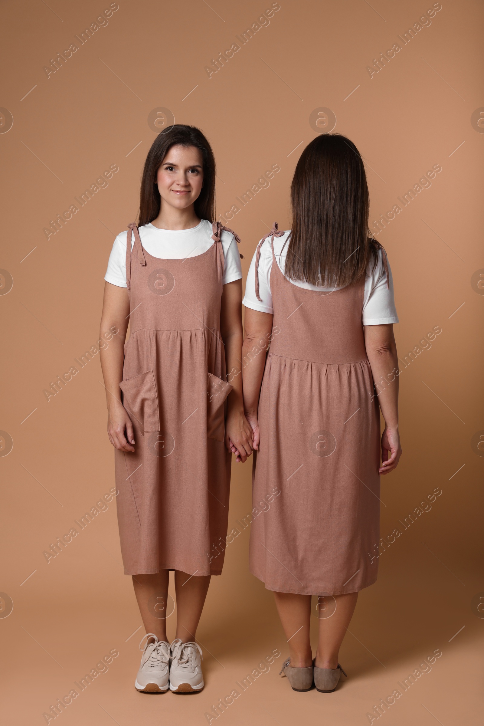 Photo of Portrait of happy twin sisters on pale brown background