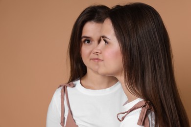 Photo of Portrait of beautiful twin sisters on pale brown background