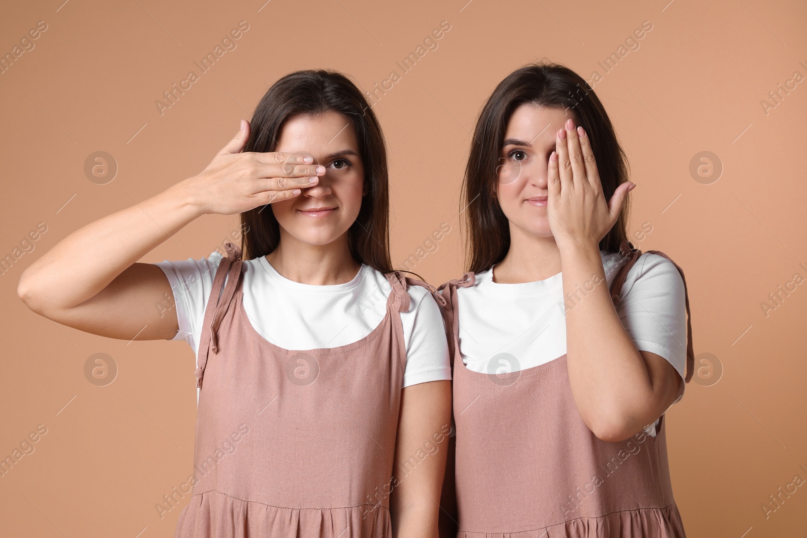 Photo of Portrait of beautiful twin sisters on pale brown background