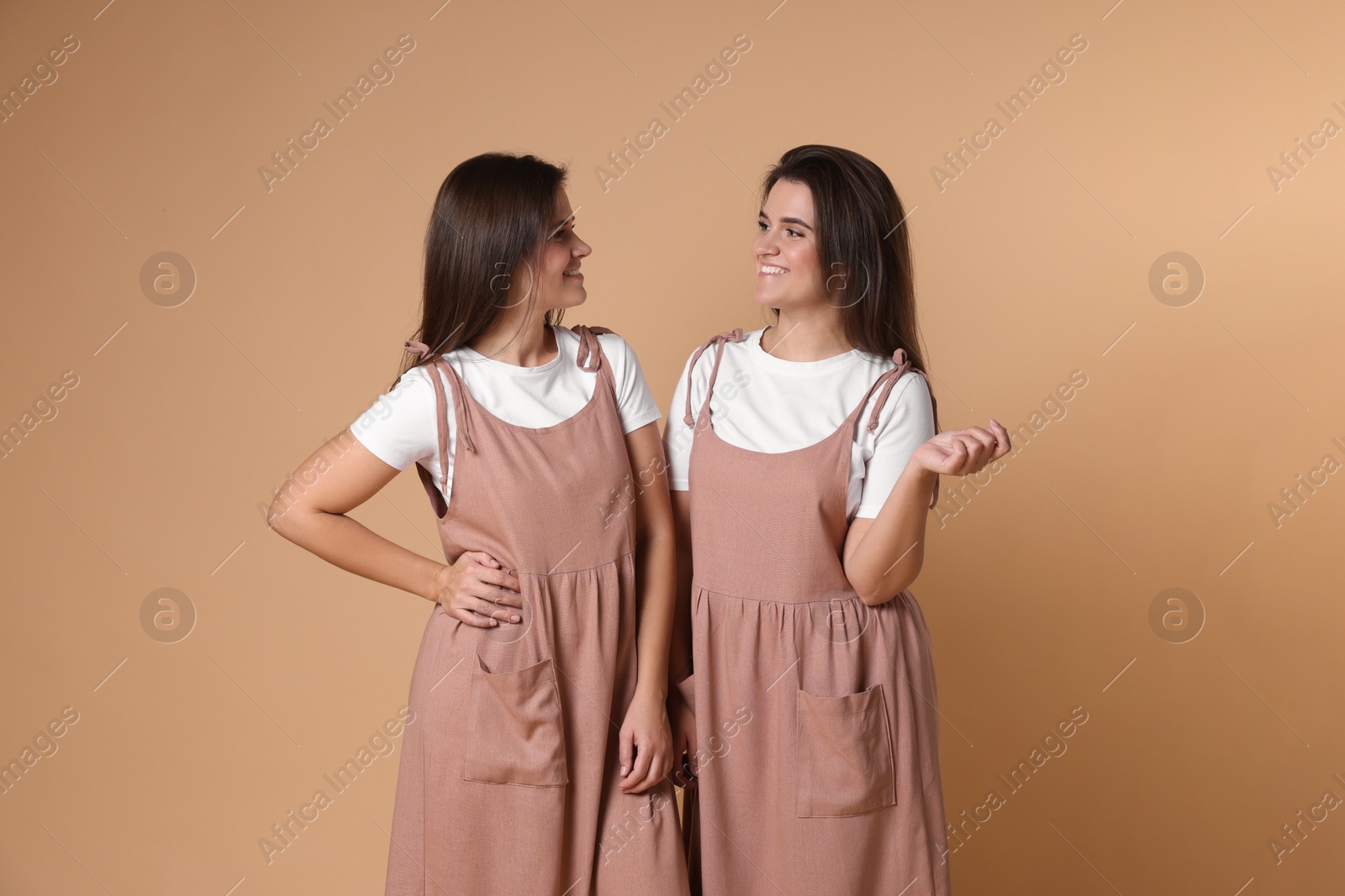 Photo of Portrait of happy twin sisters on pale brown background