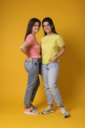 Photo of Portrait of happy twin sisters on orange background