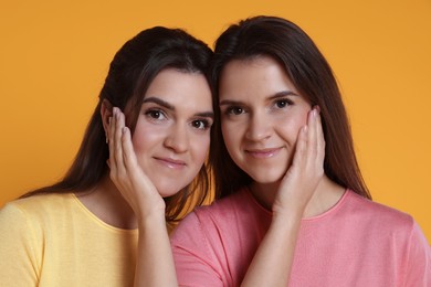 Photo of Portrait of happy twin sisters on orange background