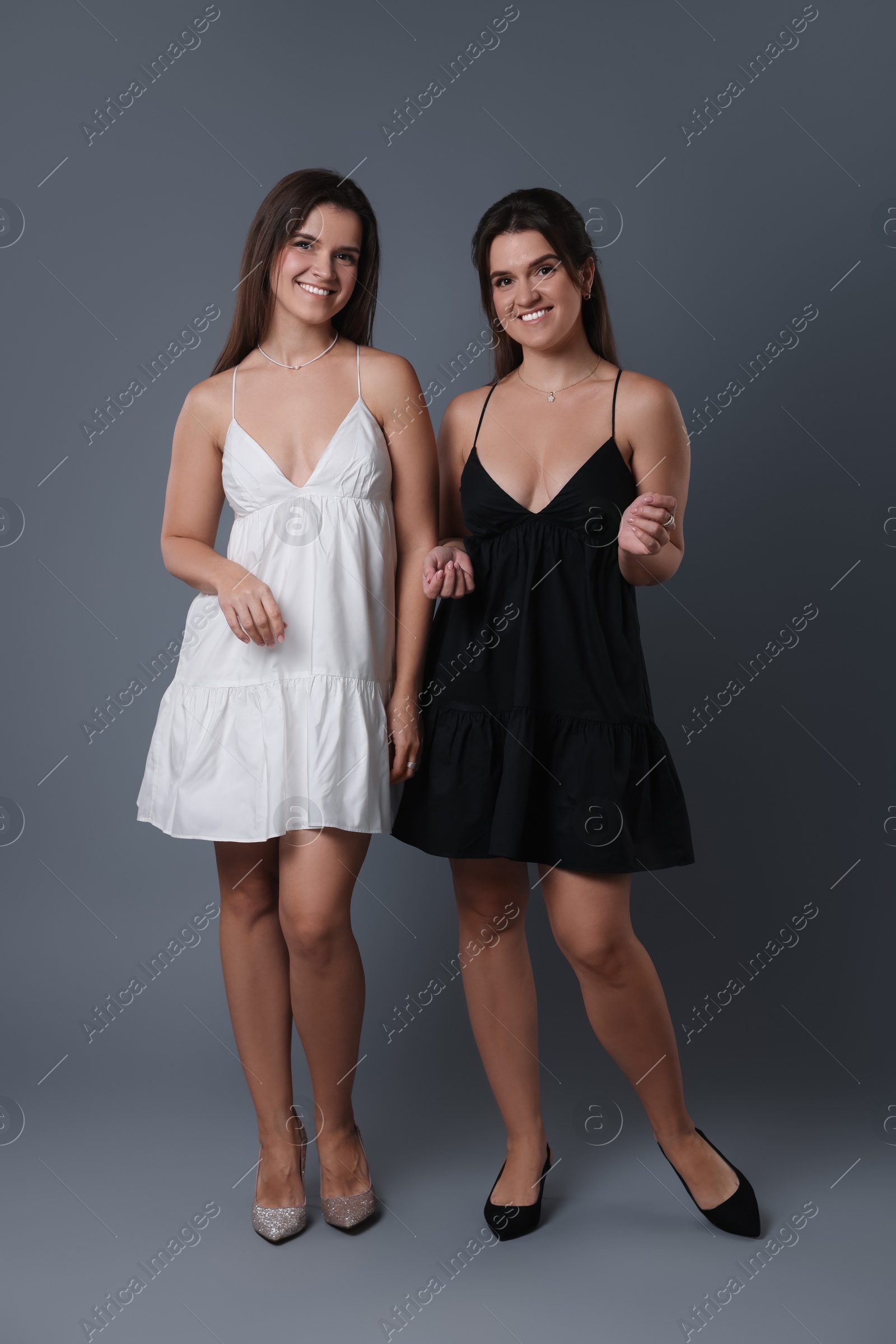 Photo of Portrait of beautiful twin sisters on grey background