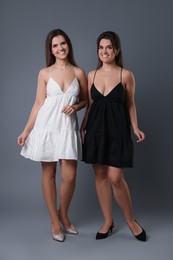 Photo of Portrait of beautiful twin sisters on grey background