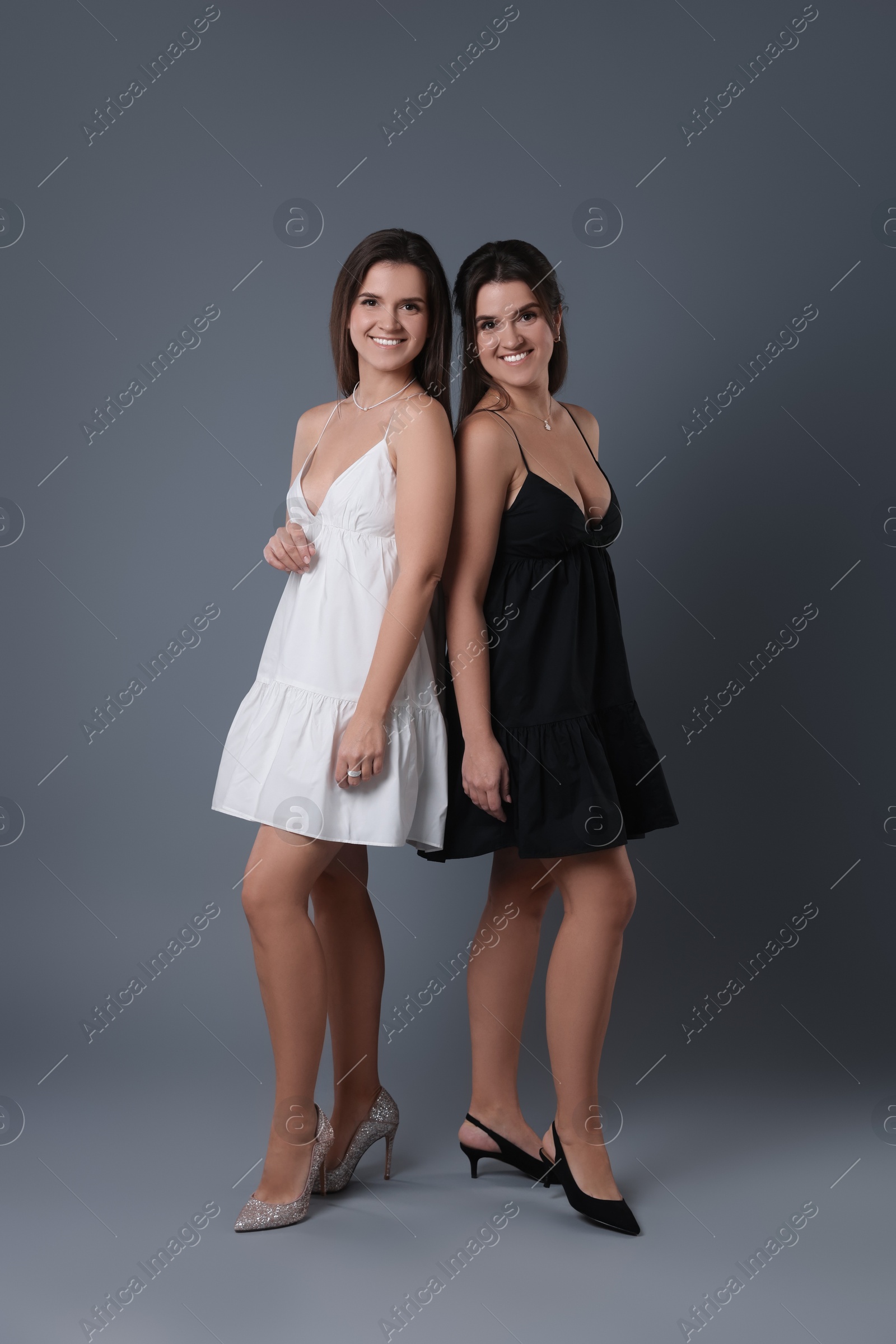 Photo of Portrait of beautiful twin sisters on grey background