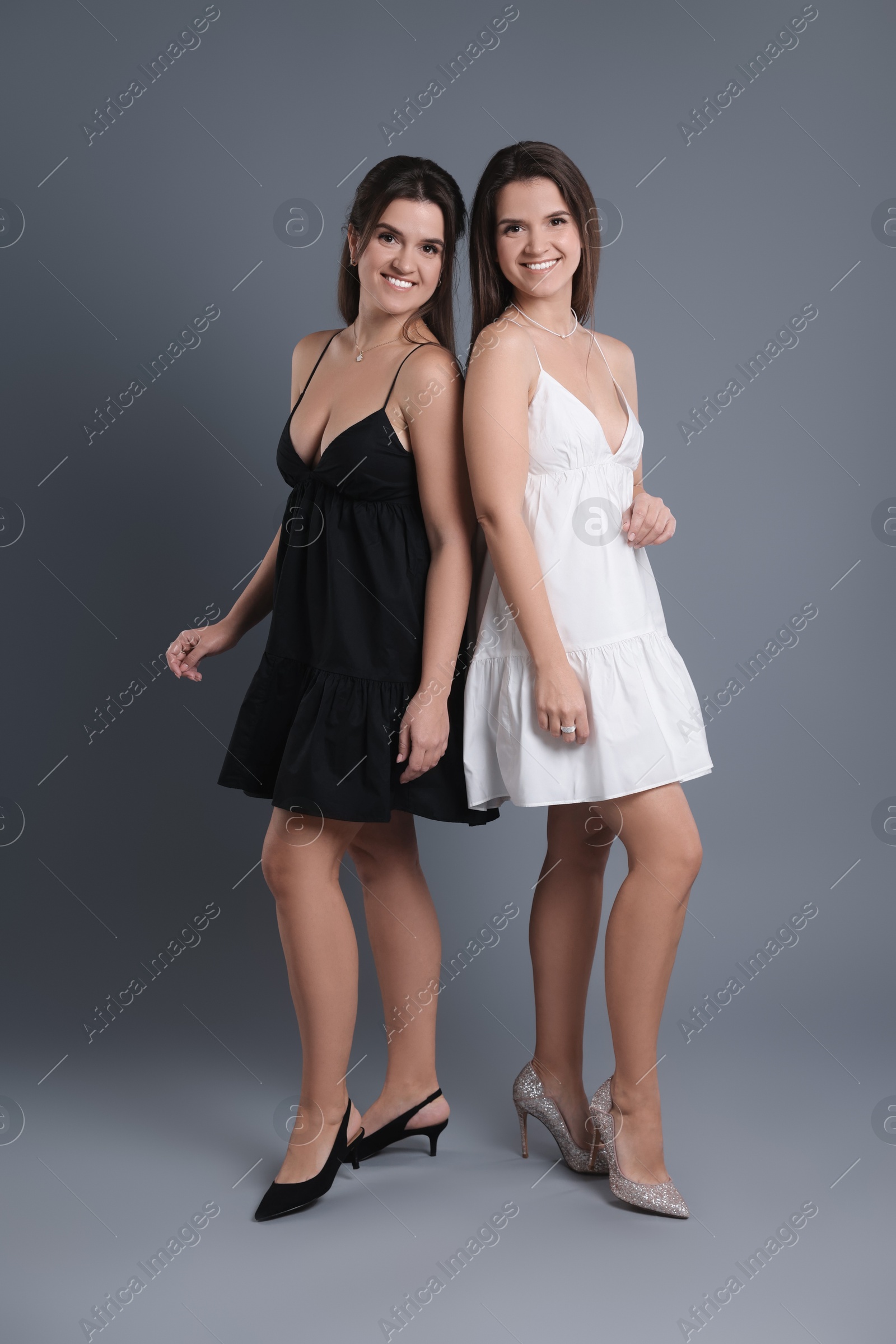 Photo of Portrait of beautiful twin sisters on grey background